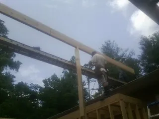 Carpenter setting a ridge beam over a new addition frame — Ice Dam Removal by Roofing Brothers in La Belle