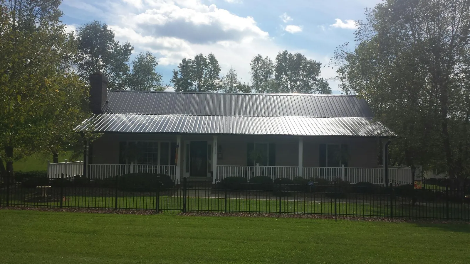 Gray metal roof on a brick ranch with a full width front porch — Gutter Guard Installation work by our crew in La Belle