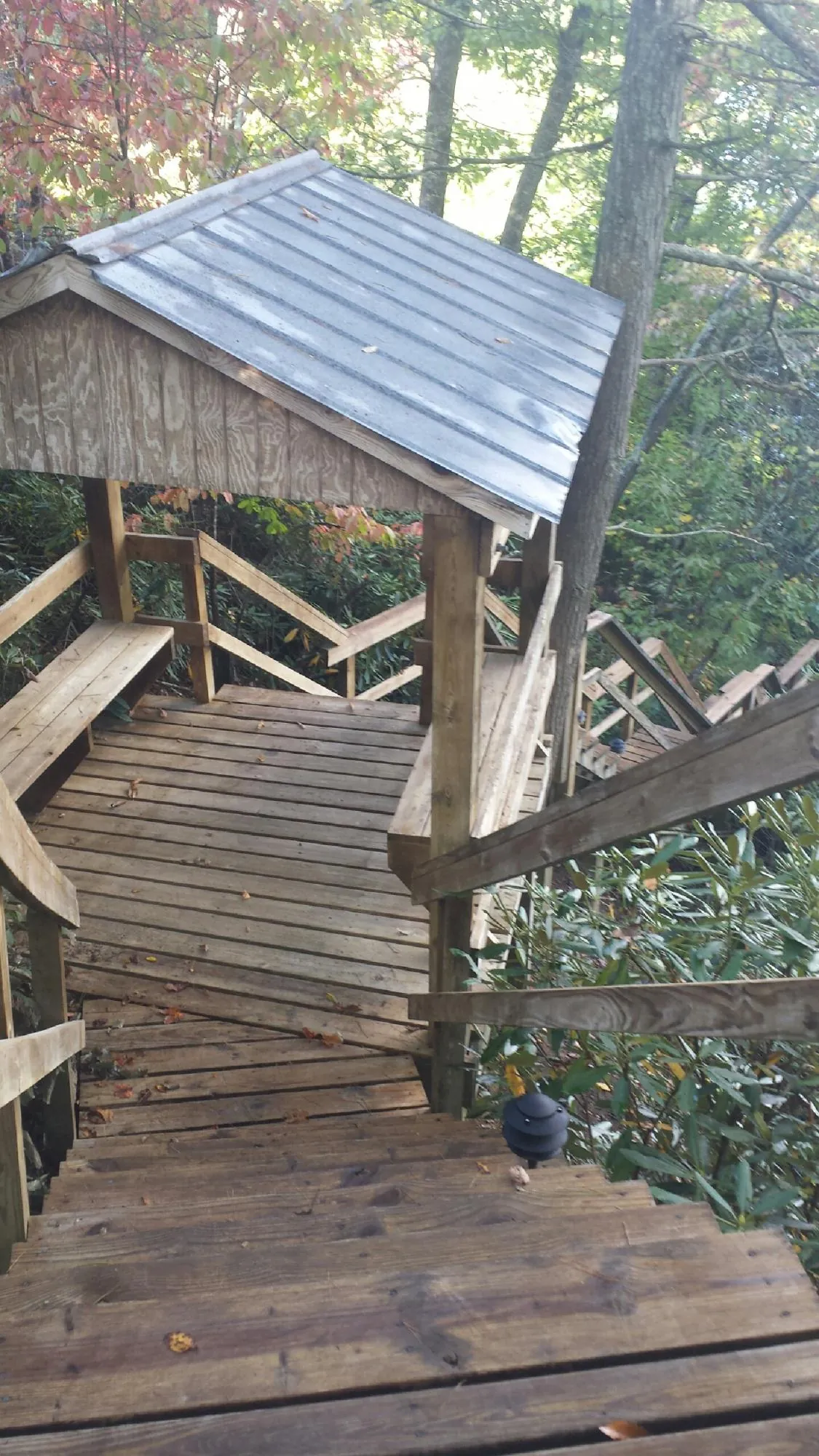 Metal roofed shelter over wooden steps on a wooded walkway — Skylight Repair & Installation work by our crew in La Belle