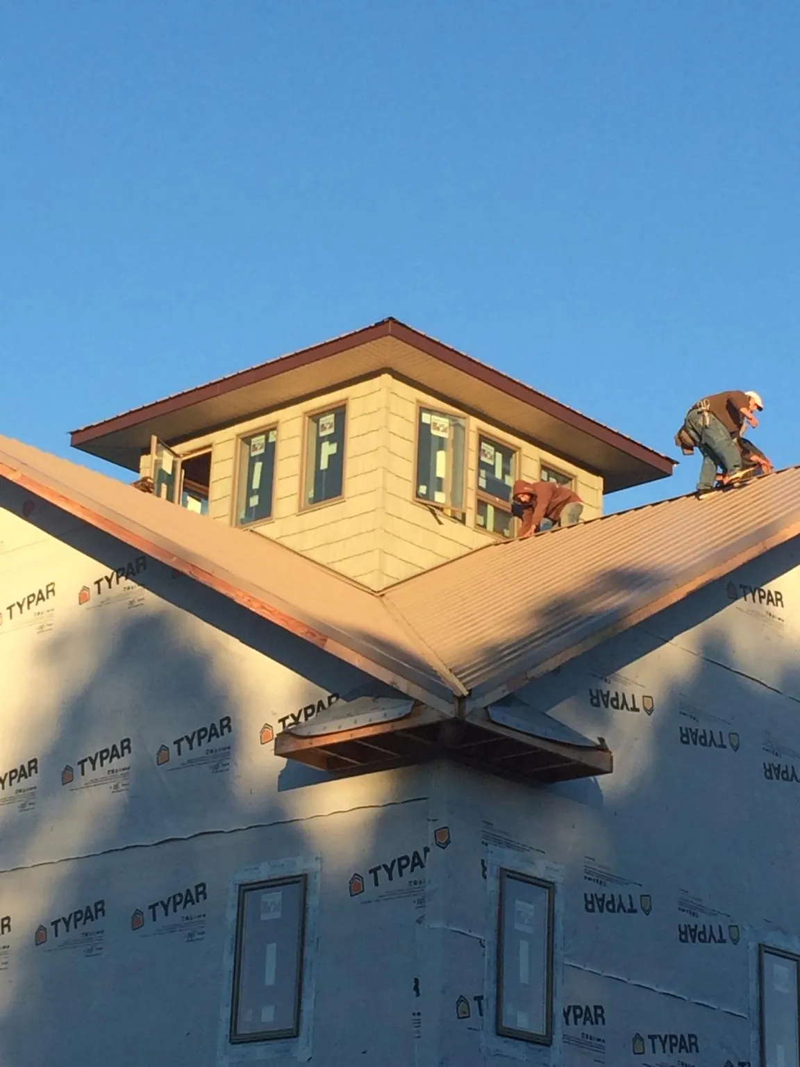 Roofers working around a rooftop cupola on a new metal roof at sunset — Roof Waterproofing in La Belle by Roofing Brothers
